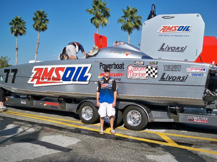 Eric Riley standing with AMSOIL sponsored offshore race boat